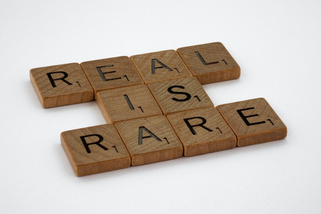 Wooden scrabble pieces on a white surface, reading 'REAL IS RARE,' symbolizing the authenticity required of brand marketing teams today