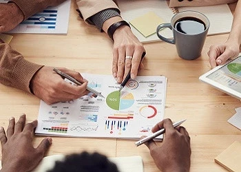 Operational excellence challenges: 5 tips to overcome these Operational excellence - People at a table with graphs and charts