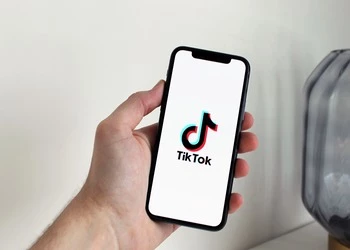 person holding phone with TikTok logo