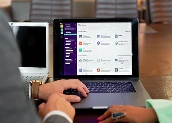 Two professionals collaborating using laptops and communication software in a business setting