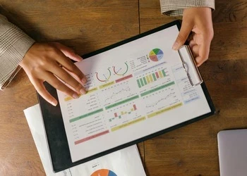 hands holding clip board of data charts