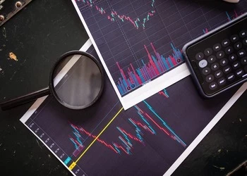 Stock market charts analyzed with a magnifying glass and calculator for financial research