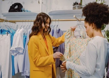 Two women shopping fashionably in a chic boutique with floral and yellow apparel