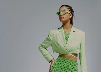 fashion model wearing green skirt, white jacket and sunglasses