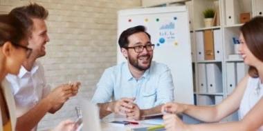 happy-employees-sitting-around-table happy-employees-sitting-around-table