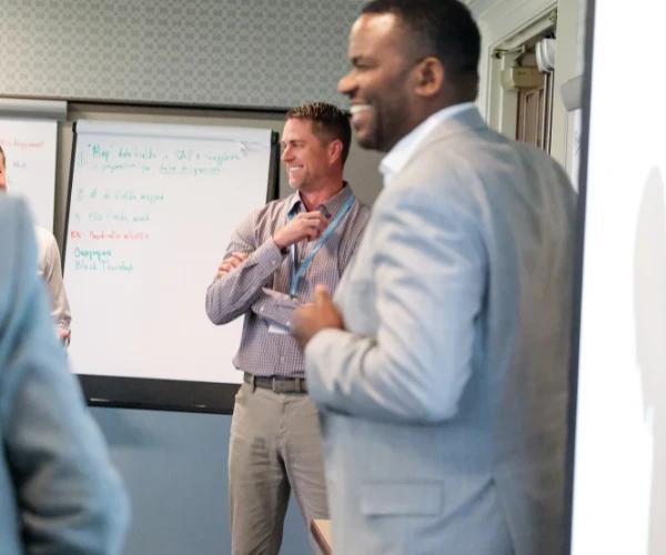 Smiling business leaders gathered around a flip chart during an executive development workshop on digital transformation